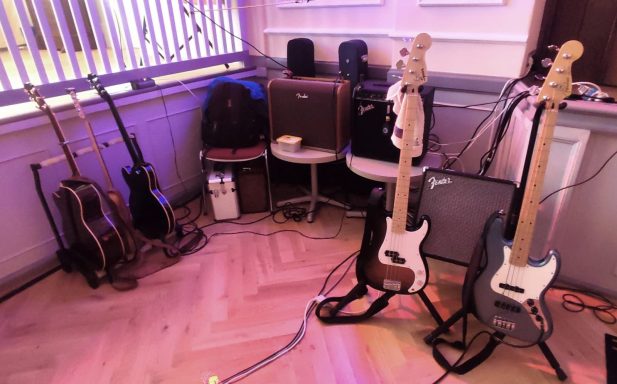 Eine Ecke mit verschiedenen Gitarren und Verstärkern in einem Veranstaltungsraum.